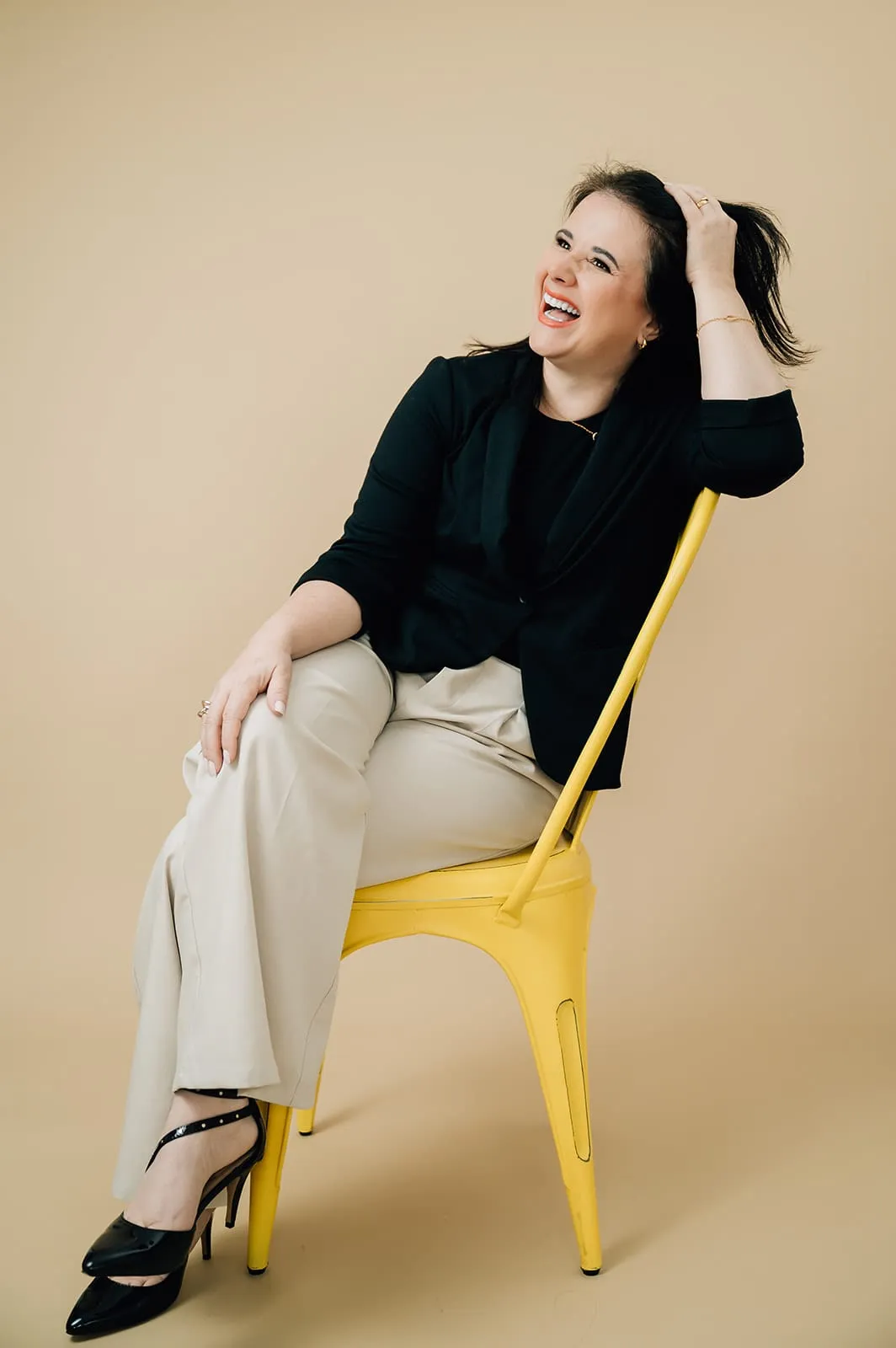 Luísa Marteleto smiling, seated in a yellow chair