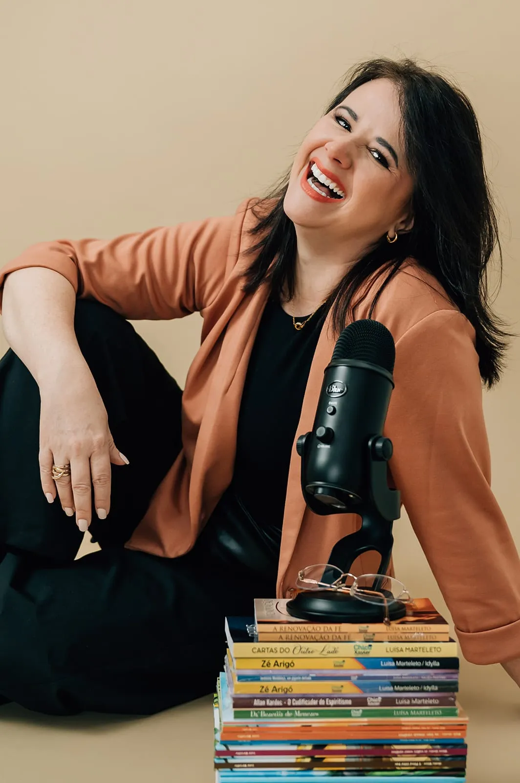Luísa Marteleto seated beside a stack of books