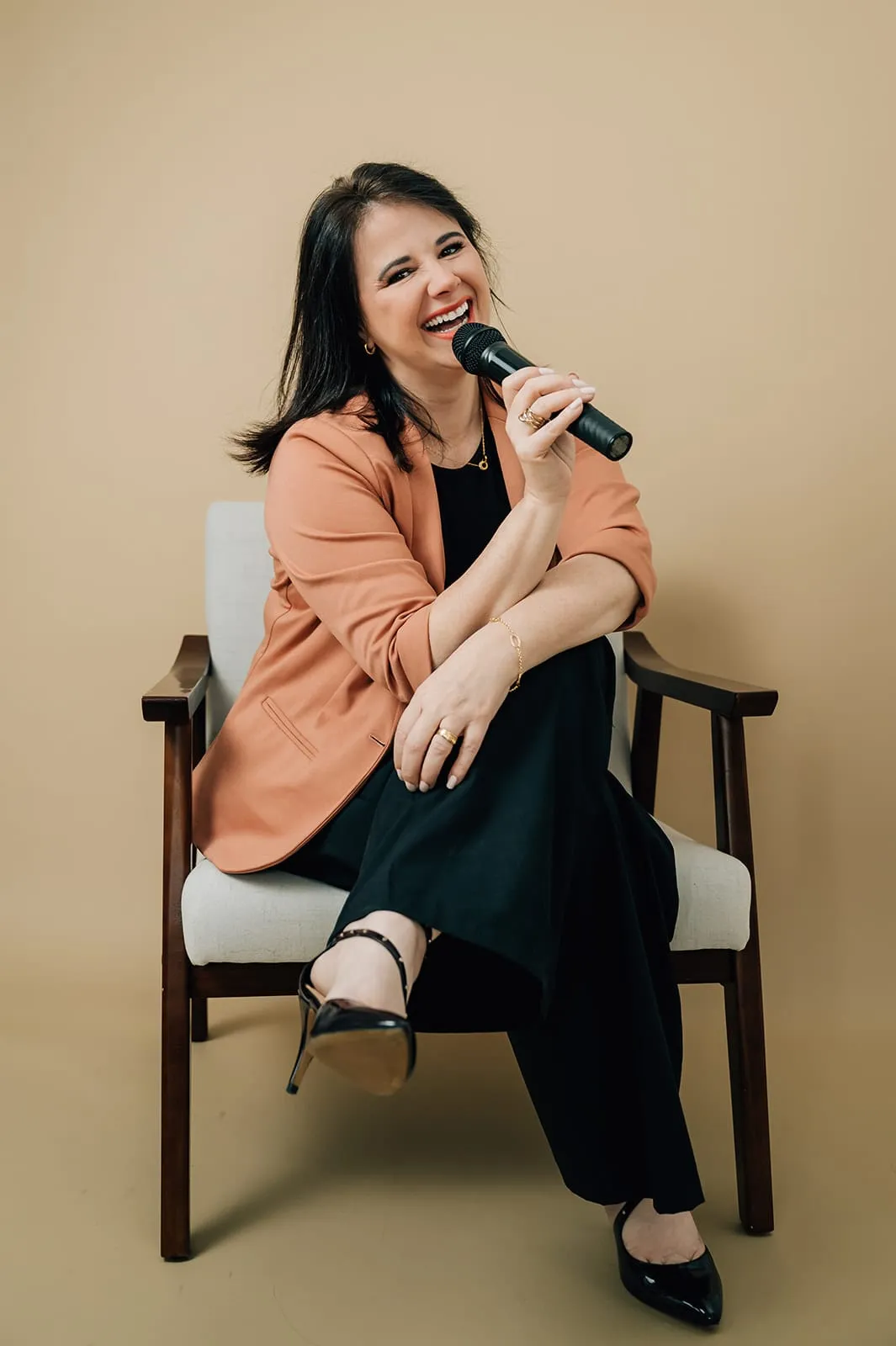 Luísa Marteleto smiling, seated with a microphone